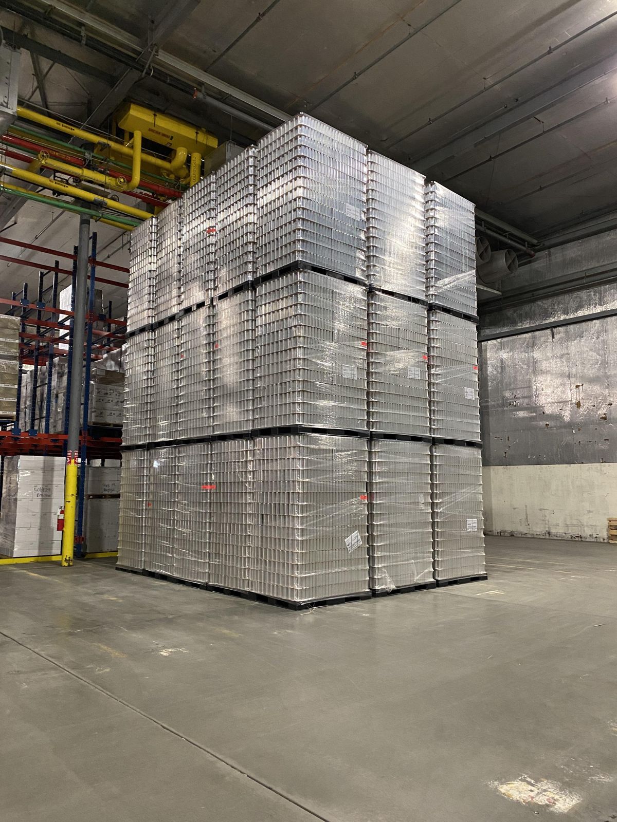 Tall stacks of empty cans on pallets in a plant warehouse