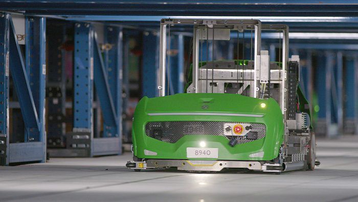 An automated guided robot carrying a load between rows of warehouse racking
